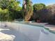 Empty swimming pool with tiled trim and steps surrounded by mature landscaping at 4928 E Philadelphia Ave, Las Vegas, NV 89104