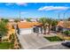 Lovely house featuring a garage, desert landscaping, green turf, and stately palm trees at 5417 Bible Cir, North Las Vegas, NV 89031