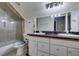 Well-lit bathroom featuring double sinks, white cabinets, and a glass enclosed shower and tub combination at 5515 N Campbell Rd, Las Vegas, NV 89149