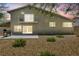 A spacious backyard with rock landscaping, patio, barbecue, and second-story balcony at dusk at 6815 Garden Grove Ave, Las Vegas, NV 89103