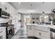 White kitchen with stainless steel appliances, white backsplash, and a view into the living room and backyard at 688 Monument Point St, Henderson, NV 89002