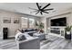 Relaxing living room featuring a sectional sofa, decorative fireplace, sleek ceiling fan, and views of the backyard at 688 Monument Point St, Henderson, NV 89002