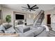 Comfortable living room with modern decor, a large ceiling fan, fireplace, and staircase to the upper level at 688 Monument Point St, Henderson, NV 89002