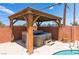 Inviting hot tub under wooden gazebo with privacy curtains in outdoor space at 704 N Wallace Dr, Las Vegas, NV 89107