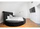 Modern bedroom with a unique round bed, hardwood floors, a TV, and bright natural light at 7215 Ullom Dr, Las Vegas, NV 89118