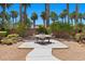 Landscaped backyard with a patio area, perfect for outdoor dining, surrounded by lush palm trees at 8021 Glacier Falls St, North Las Vegas, NV 89085