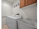 Bright laundry room featuring a white washer and dryer, utility sink, and upper cabinets at 8021 Glacier Falls St, North Las Vegas, NV 89085