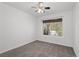 A carpeted bedroom featuring a ceiling fan and a window looking out to trees and vegetation at 920 Serpentina Ave, Las Vegas, NV 89123