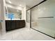 Modern bathroom with a double vanity, large mirror, and a sleek glass-enclosed shower with a built-in seat at 9348 Wildcat Peak St, Las Vegas, NV 89178