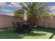Artificial grass backyard features outdoor dining under a large palm tree and a block wall at , North Las Vegas, NV 89031