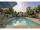 Inviting community pool with a shaded umbrella, surrounded by a fence at 10414 Midseason Mist St, Las Vegas, NV 89183