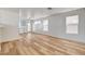 Expansive living area featuring wood-look flooring, white walls, and large windows for natural light, seamlessly flowing to the kitchen at 1716 Klamath Falls Way, Las Vegas, NV 89128