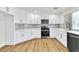 Renovated kitchen with white cabinets, stainless steel appliances, gray backsplash and light vinyl flooring at 2112 Hollow Oak Ave, North Las Vegas, NV 89031