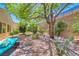 Lush backyard offers a serene escape with trees, chaise lounge, and space for relaxation and enjoyment at 2205 Sandstone Cliffs Dr, Henderson, NV 89044