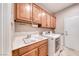 Functional laundry room with ample cabinet space, a utility sink, and modern washer and dryer at 2205 Sandstone Cliffs Dr, Henderson, NV 89044