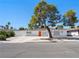 Charming single-story home featuring a white facade, orange front door and mature landscaping at 2245 Sombrero Dr, Las Vegas, NV 89169