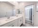 A bright bathroom featuring a double sink vanity, large mirror and a shower/tub combo with neutral tile at 3821 Nesting Wren Dr, North Las Vegas, NV 89084