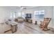 Comfortable living room with modern gray wood floors, rocking chair, and a large TV for entertainment at 3821 Nesting Wren Dr, North Las Vegas, NV 89084