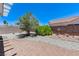 Fully fenced backyard features gravel, mature trees, rock features, and a fountain at 4724 Victoria Beach Way, Las Vegas, NV 89130