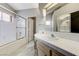 Bright bathroom featuring double sinks, a large mirror, and a tiled tub with glass door at 4724 Victoria Beach Way, Las Vegas, NV 89130