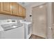Functional laundry room features a modern washer and dryer, wood-look floors, and storage cabinets at 5001 Morning Falls Ave, Las Vegas, NV 89131