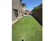 This backyard features artificial turf, a patio with seating, and a perimeter fence for privacy at 5414 Enchanted Rose St, Las Vegas, NV 89148