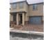 Two-story home with tan stucco, stone accents, a two-car garage, and a paver driveway and walkway at 5414 Enchanted Rose St, Las Vegas, NV 89148