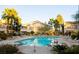 Community pool surrounded by lounge chairs and lush landscaping at 5710 E Tropicana Ave # 2225, Las Vegas, NV 89122
