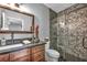 Bathroom featuring a glass shower door with textured tile surround, dark vanity, and granite countertop at 5805 Cabo San Lucas Ave, Las Vegas, NV 89131