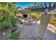 Outdoor living space with shaded seating, a fireplace, and a built-in TV, surrounded by lush tropical foliage at 5805 Cabo San Lucas Ave, Las Vegas, NV 89131