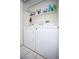 Compact laundry area with a side-by-side washer and dryer setup, and overhead shelving for convenient storage at 6249 Halehaven Dr, Las Vegas, NV 89110