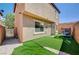 View of a backyard with a trampoline, gray stucco house, artificial grass, and brick fence at 635 Taliput Palm Pl, Henderson, NV 89011