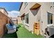 View of a backyard with a chair, trampoline, tan house with an air conditioning unit, and artificial grass at 635 Taliput Palm Pl, Henderson, NV 89011