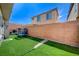 View of a backyard with a trampoline, brick wall, artificial grass, and a covered patio at 635 Taliput Palm Pl, Henderson, NV 89011