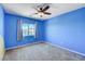 Bright blue bedroom featuring a window, ceiling fan, and gray carpet at 6569 Cedar Waxwing St, North Las Vegas, NV 89084