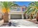 Charming two-story home with a tile roof, desert landscaping, and palm trees framing the front entrance and two-car garage at 6569 Cedar Waxwing St, North Las Vegas, NV 89084