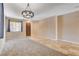 Light-filled living room with plush carpet, tile accents, a statement chandelier, and a wooden door at 6569 Cedar Waxwing St, North Las Vegas, NV 89084