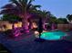 Backyard pool and landscaped area with palm trees illuminated with purple lighting at 6614 Collingsworth St, Las Vegas, NV 89131