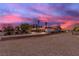 Wide shot of a house with a long driveway and desert landscaping under a vibrant sunset sky at 825 W Ryan Ave, Overton, NV 89040