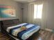 This bedroom features striped bedding, natural light, a modern black lamp, and wood-look flooring for a cozy and stylish retreat at 8901 Kingswood Dr, Las Vegas, NV 89147