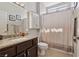 Well-lit bathroom featuring granite counters, dark cabinets and a shower/tub combo with decorative shower curtain at 10428 Villa Ridge Dr, Las Vegas, NV 89134