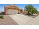 Tan single-story home with a two-car garage, desert landscaping, and a wide driveway at 10428 Villa Ridge Dr, Las Vegas, NV 89134