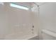 All white tiled tub-shower combination and toilet beneath a small window at 1069 Aspen Cliff Dr, Henderson, NV 89011