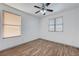 Bright bedroom featuring wood-look floors, ceiling fan, and dual windows for natural light at 1069 Aspen Cliff Dr, Henderson, NV 89011