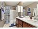 Well-lit bathroom with a vanity, cabinets, mirror, shower with patterned curtain and toilet at 135 Cadrow Castle Ct, Las Vegas, NV 89148