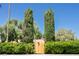View of a wood entrance gate with two tall, thin trees and manicured bushes at 1911 Valley Dr, Las Vegas, NV 89108