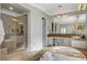 Bright bathroom featuring a glass-enclosed shower, soaking tub, and dual vanity with tile counters at 2172 De Rouge Ave, Henderson, NV 89044