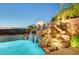 Stunning rock waterfall cascades into a refreshing pool, surrounded by tropical plants at 2172 De Rouge Ave, Henderson, NV 89044