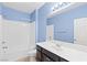 Bright bathroom features blue walls, a shower-tub combo, a large mirror, and a modern dark vanity at 3012 Chiefs Ct, North Las Vegas, NV 89032