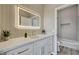 Modern bathroom with a brightly lit mirror, white cabinets, gold hardware, and a tub at 3218 Squire St, Las Vegas, NV 89135